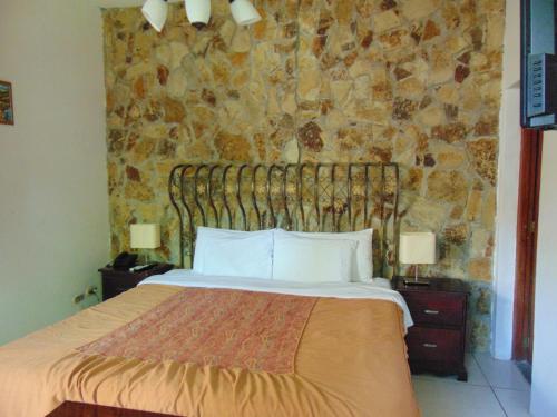 a bedroom with a bed and a stone wall at Managua Hills in Managua