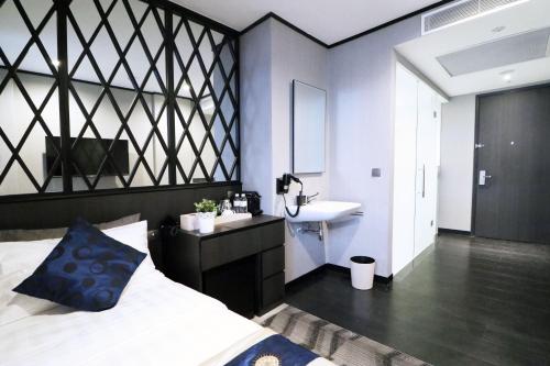 a bedroom with a bed and a sink and a mirror at Hotel NuVe Urbane in Singapore