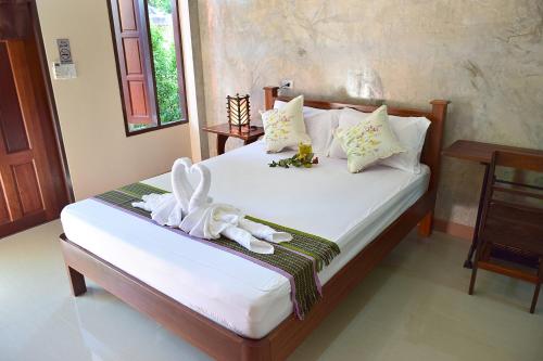 a bedroom with a bed with white towels on it at Siam Guesthouse in Kanchanaburi