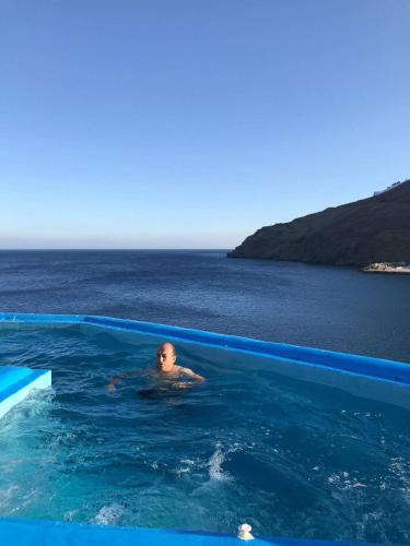 a man in a swimming pool with the ocean in the background at Caldera Studios in Astypalaia Town