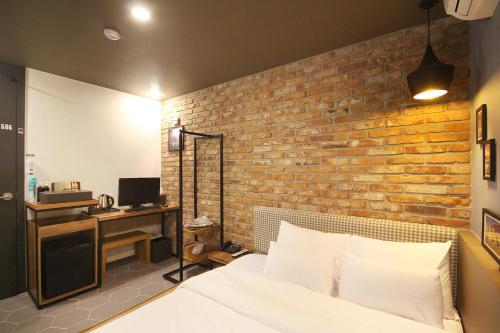 a bedroom with a brick wall and a bed and a desk at Gray Hotel Busan Station in Busan