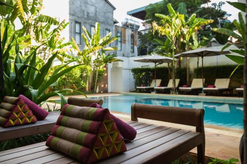 a wooden bench with pillows next to a swimming pool at Apsara Centrepole Hotel in Siem Reap