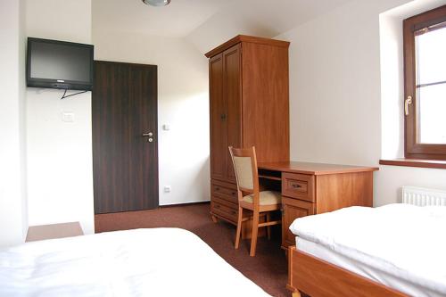 a bedroom with a desk and a bed and a cabinet at Penzion U Kostela in Újezd