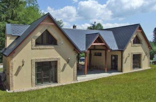 a house with a black roof on a green field at Three Chalets Vrútky in Vrútky
