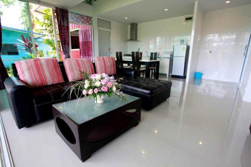 a living room with a couch and a table with flowers at Saree Lagoon Villa Koh Samui in Lipa Noi