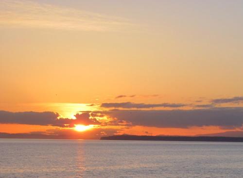 a sunset over the water with the sun setting at Ocean Promenade Hotel in White Rock