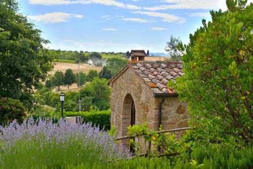 un edificio de piedra en un jardín con flores púrpuras en Agriturismo Zampugna, en Montefollonico