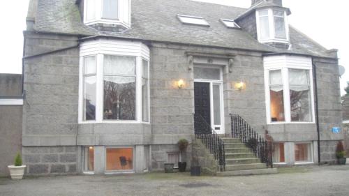a gray brick house with stairs and windows at Station View Guest House in Dyce