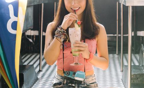 a woman with a camera holding a drink at Cara Cara Inn in Kuta