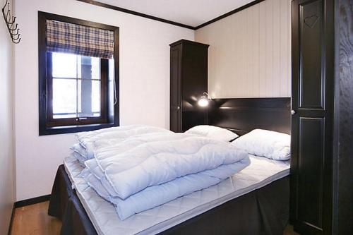 a bedroom with a bed with white sheets and a window at Alpin Apartments Sørlia in Hafjell