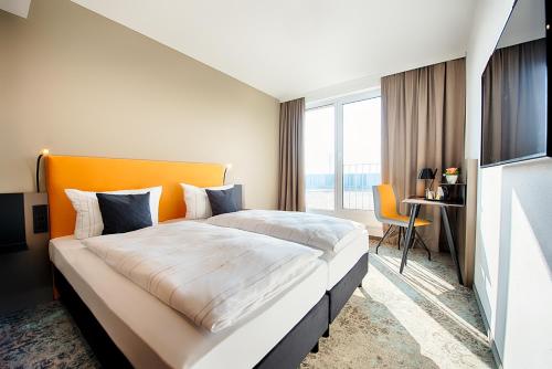 um quarto de hotel com uma cama grande e uma secretária em LOGINN Hotel Leipzig em Leipzig