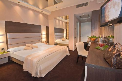 チェザーノ・マデルノにあるAS ホテル デイ ジョーヴィの大型ベッドとテレビが備わるホテルルームです。