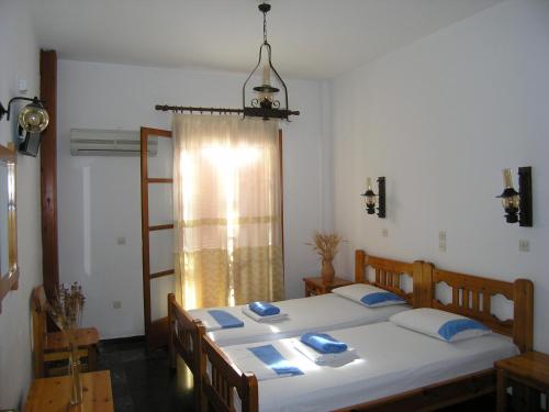 una camera da letto con un grande letto bianco con cuscini blu di Pension Chanioti a Paroikia