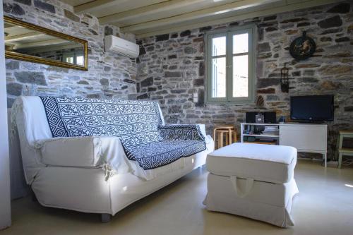 a living room with a white couch and a tv at Serifos Dream Houses near the sea in Ganema