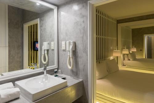 uma casa de banho com um lavatório, um espelho e uma cama em Motel Tropicana em Vila Nova de Gaia