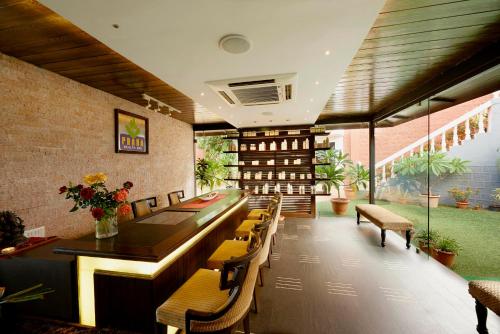 a restaurant with a long bar with chairs and plants at Brightland Resort & Spa in Mahabaleshwar