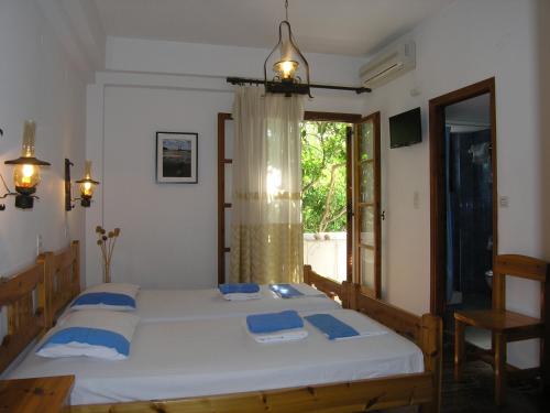 a bedroom with a bed with blue pillows and a window at Pension Chanioti in Parikia