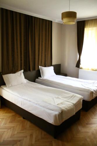 2 Betten in einem Hotelzimmer mit Fenster in der Unterkunft Guest House Central in Kardschali