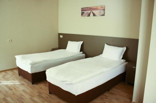2 Betten in einem kleinen Zimmer mit weißer Bettwäsche in der Unterkunft Guest House Central in Kardschali