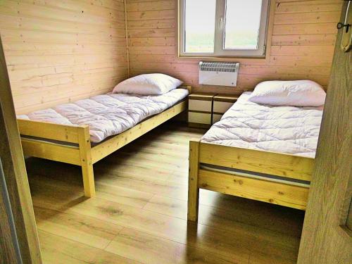 dwa łóżka pojedyncze w pokoju z drewnianą podłogą w obiekcie Domki Śnieżka w mieście Wojcieszyce