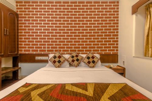um quarto com uma cama com uma parede de tijolos em Hotel Mogul Palace - Near CST Station em Mumbai