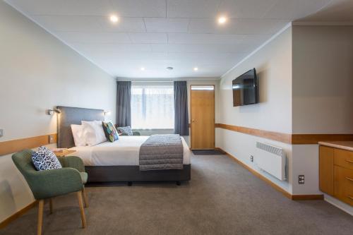 a hotel room with a bed and a chair at Dunedin Motel and Villas in Dunedin