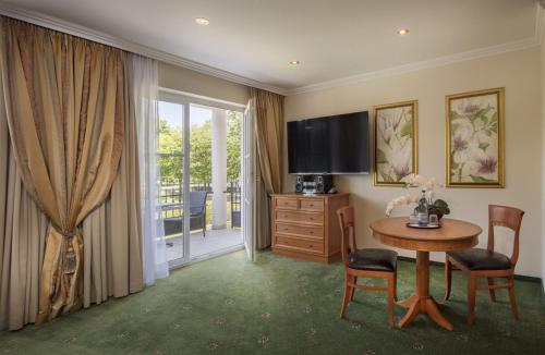 a hotel room with a table and a television at Hotel Schweizer Hof Thermal und Vital Resort in Bad Füssing