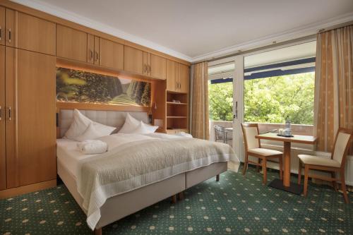 a bedroom with a bed and a desk and a window at Hotel Schweizer Hof Thermal und Vital Resort in Bad Füssing