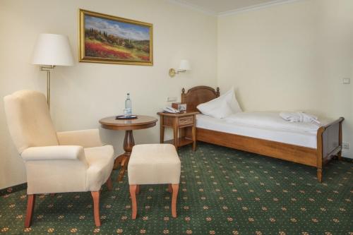 a hotel room with a bed and a table and chairs at Hotel Schweizer Hof Thermal und Vital Resort in Bad Füssing