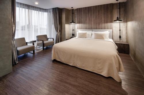 a hotel room with a large bed and a chair at S Hadyai Hotel in Hat Yai