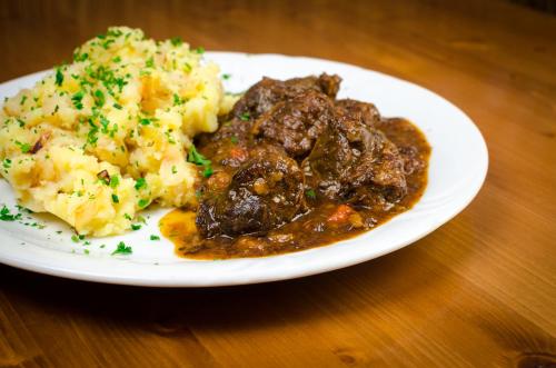 a plate of food with meat and potatoes on a table at Penzion U Kostela in Újezd