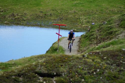 a person riding a bike down a path next to a river at Sport Garni Kapplerhof – Ischgl/Kappl in Kappl