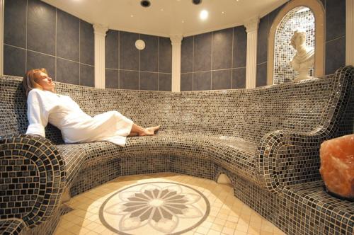 a woman sitting on a couch in a bath room at Hotel Schweizer Hof Thermal und Vital Resort in Bad Füssing