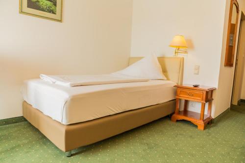 a bed in a hotel room with a night stand at Familie Hopfeld - Hotel Dreikönigshof in Stockerau