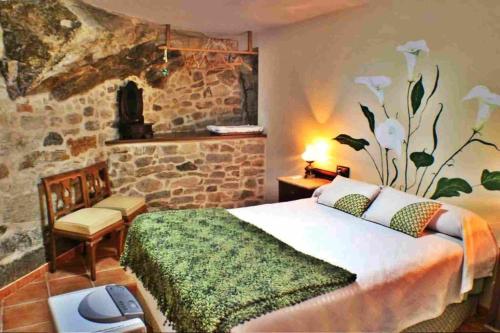 a bedroom with a bed and a stone wall at Casa Combarro in Combarro