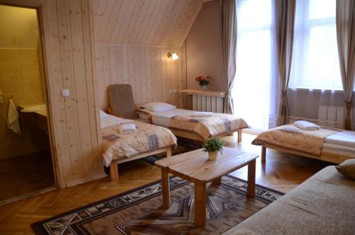a living room with three beds and a table at Pensjonat Adria in Zakopane