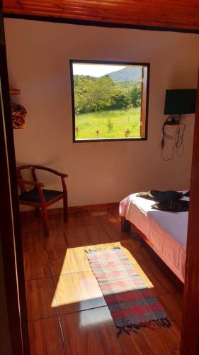 a bedroom with a bed and a window at Chalé Primavera - Eubiose in São Thomé das Letras