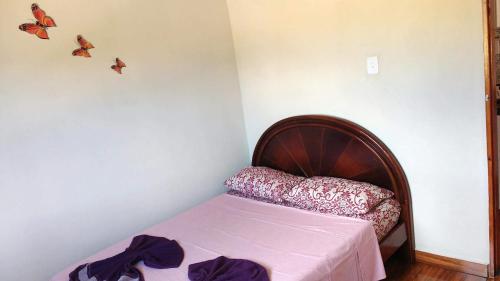 a small bedroom with a bed with butterflies on the wall at Chalé Primavera 1 in São Thomé das Letras