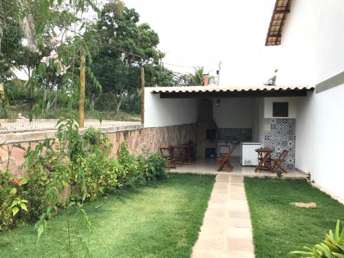 a backyard of a white house with a table and chairs at Apartamento 05 Vivendas do Serrano - Lençóis in Lençóis