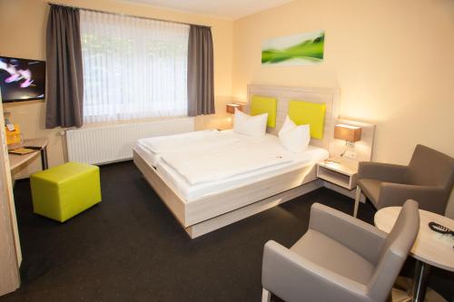 une chambre d'hôtel avec un grand lit et des chaises dans l'établissement Hotel Im Tannengrund, à Langelsheim