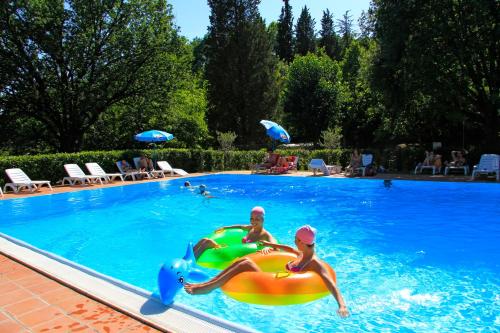 two people playing in a swimming pool with an inflatable at Camping Siena Colleverde in Siena