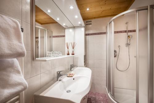 a white bathroom with a shower and a sink at Residence Ciasa Planat in San Cassiano