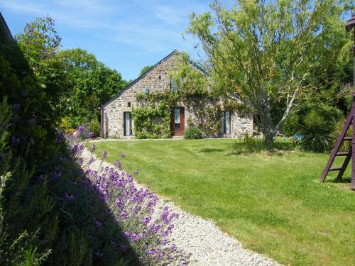 een stenen huis met paarse bloemen ervoor bij Emerald Coast Gites and Lodge in Hénansal