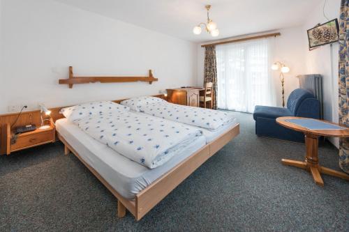1 dormitorio con 2 camas, mesa y silla en Hotel Rhodania en Zermatt