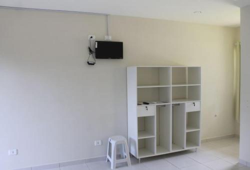 a room with a white shelf and a tv on a wall at Pousada Caminho das Ilhas in Pontal do Paraná