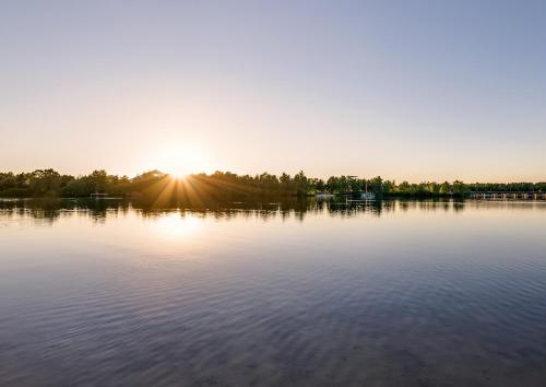 a view of a lake with the sun setting at Center Parcs Vossemeren in Lommel