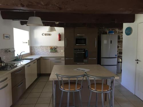 a kitchen with a large island with two bar stools at Emerald Coast Gites and Lodge in Hénansal