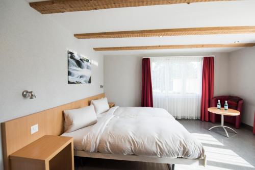 Schlafzimmer mit einem Bett und einem Fenster mit roten Vorhängen in der Unterkunft Hotel Restaurant Neuhaus in Hertenstein