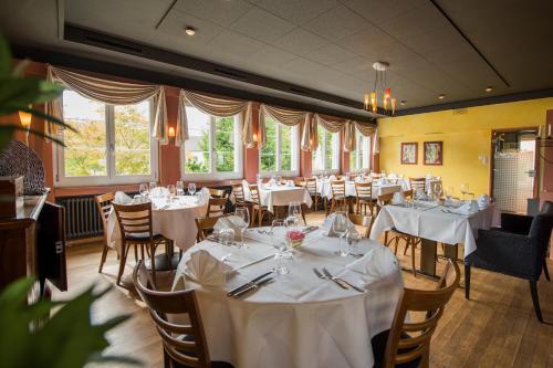 a dining room with white tables and chairs and windows at Hotel Restaurant Neuhaus in Nussbaumen