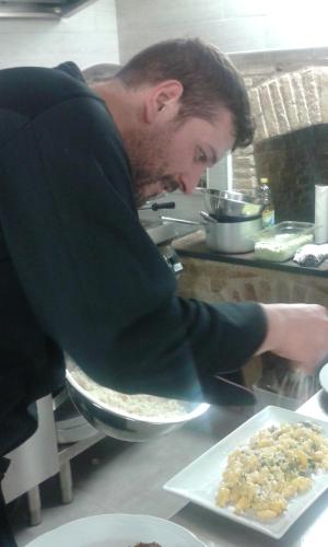a man in a kitchen preparing food on a plate at Masseria Celentano Relais & Agriturismo in San Severo